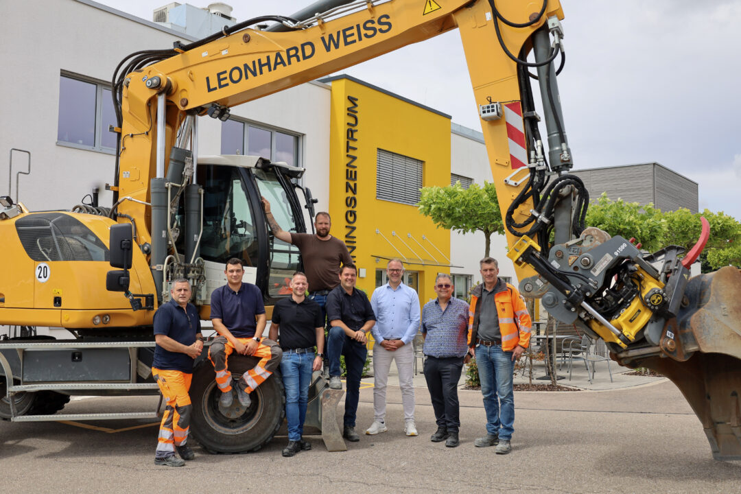 Équipe LEONHARD WEISS et ZD Solution devant une pelle sur pneus avec tiltrotateur ZD